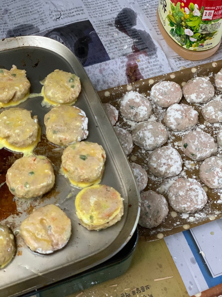조리 중인 다양한 생선 전과 미트볼이 담긴 쟁반, 김밥용 재료가 포개져 있는 모습.