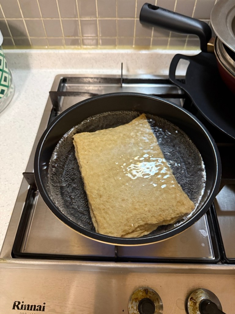 Dropping thin strips of fish cakes into a pot of rolling boiled water.