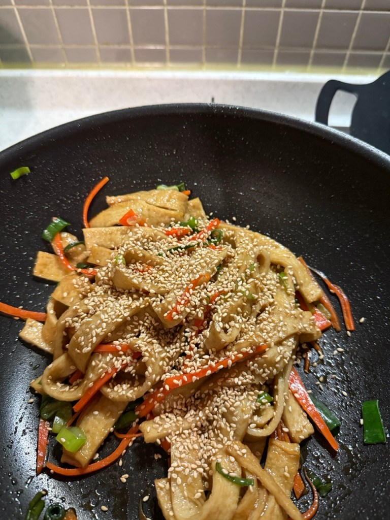 Drizzling fragrant sesame oil and sprinkling roasted seeds over the dish.