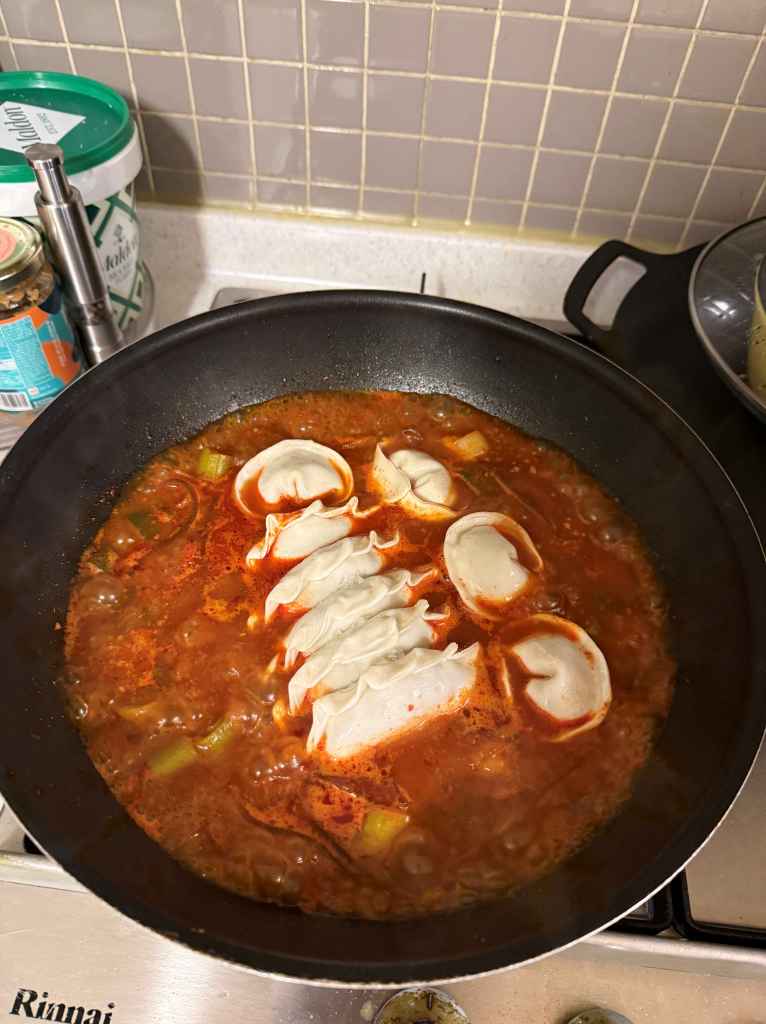 Homemade spicy dumpling stew boiling vigorously on the stove.