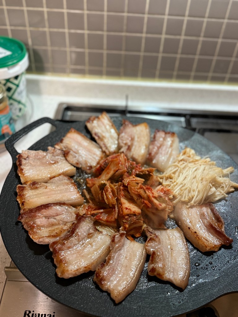 A full Korean BBQ table set up at home with grilled pork belly, kimchi, and side dishes.