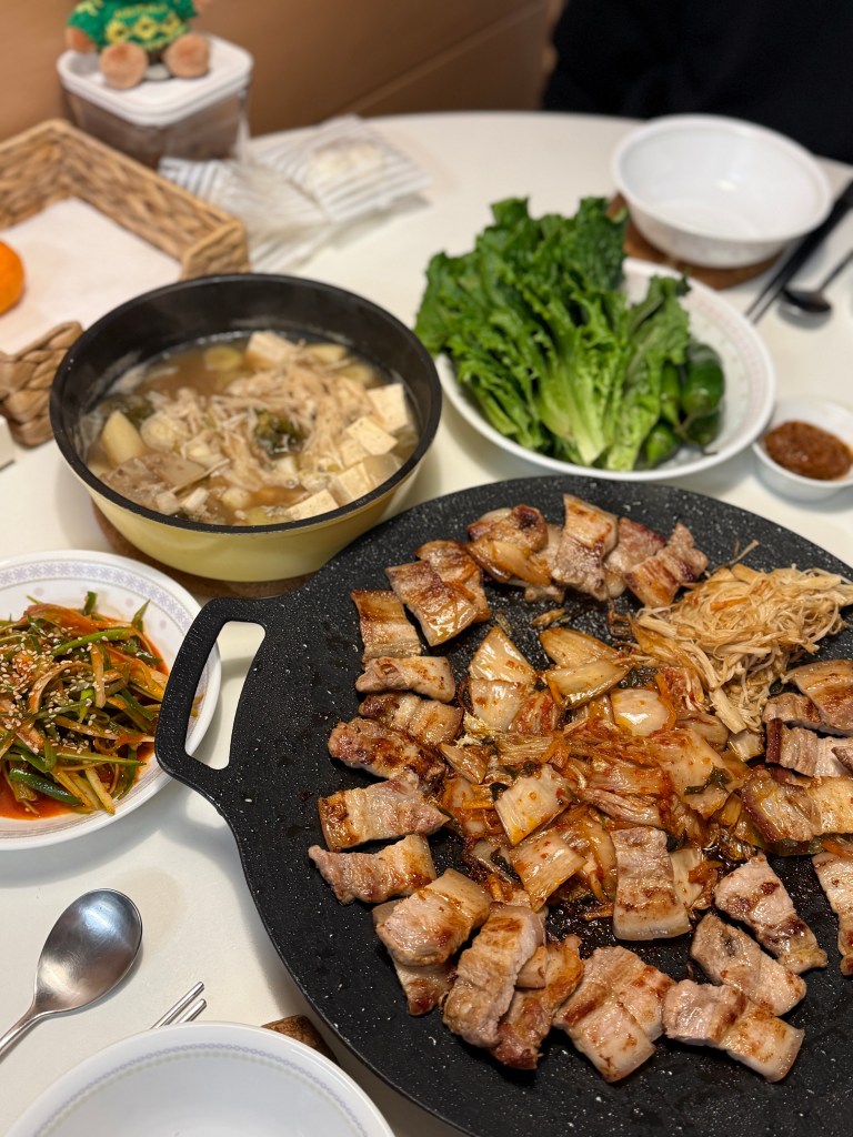 A full Korean BBQ table set up at home with grilled pork belly, kimchi, and side dishes.