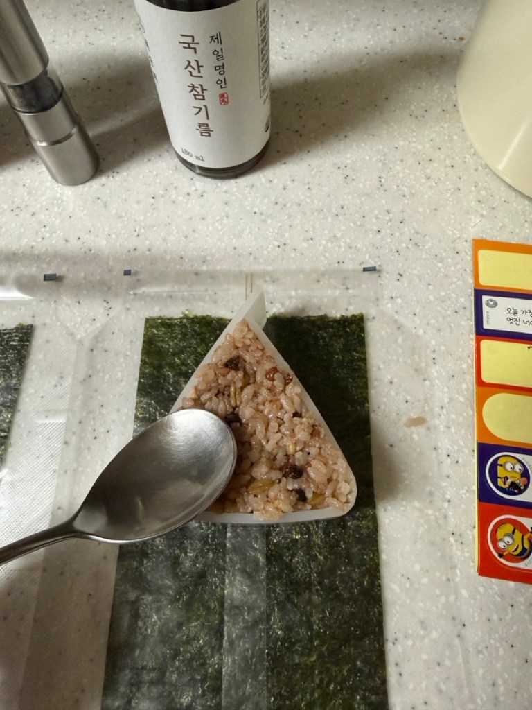 Placing tuna mayo filling inside the rice triangle.