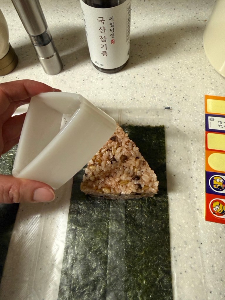Placing tuna mayo filling inside the rice triangle.
