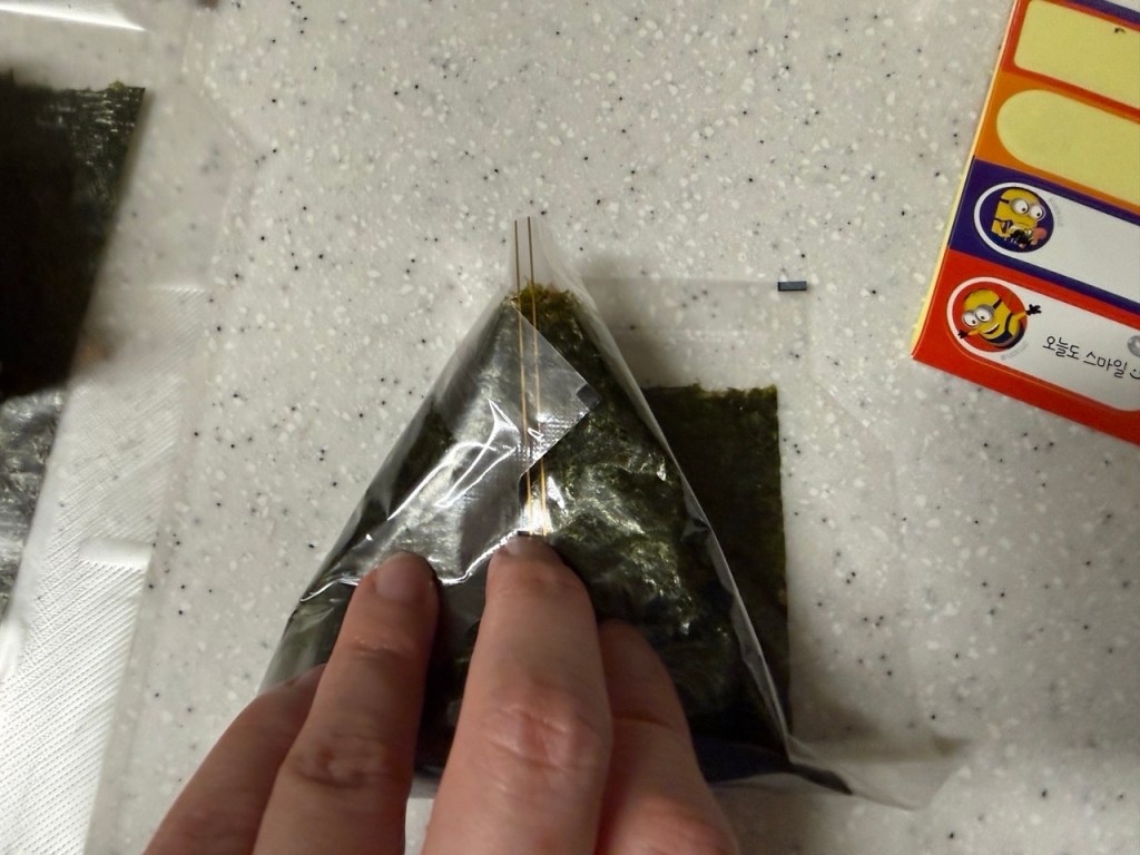 Wrapping the rice with a sheet of dried seaweed.