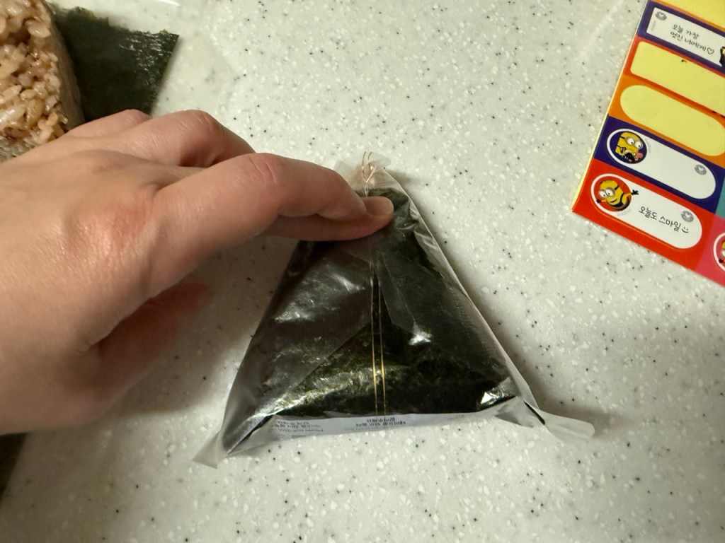 Wrapping the rice with a sheet of dried seaweed.