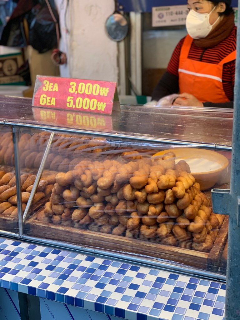 The colorful and busy display of various donuts and snacks at a market stall.
