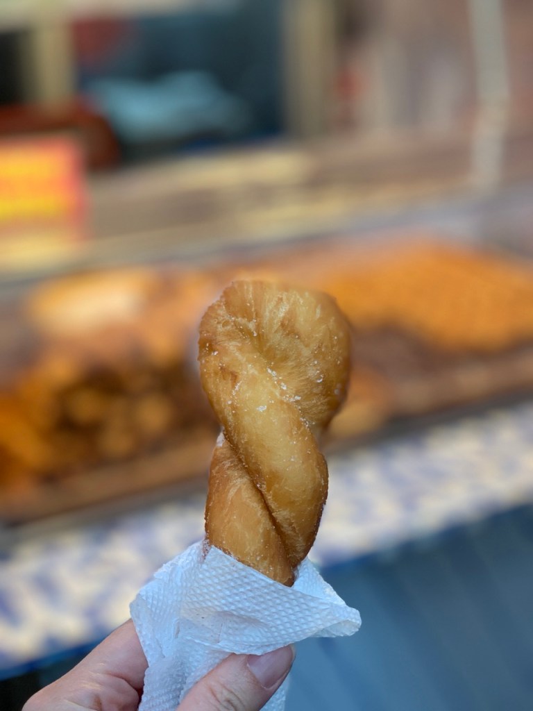 Close-up of a golden brown twisted donut coated with sweet granulated sugar.