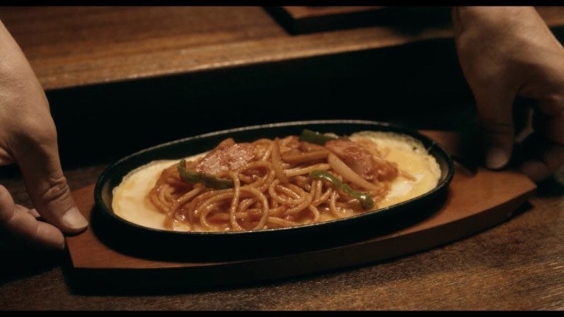 A close-up of steaming hot Napolitan spaghetti, capturing the cozy atmosphere of the diner.