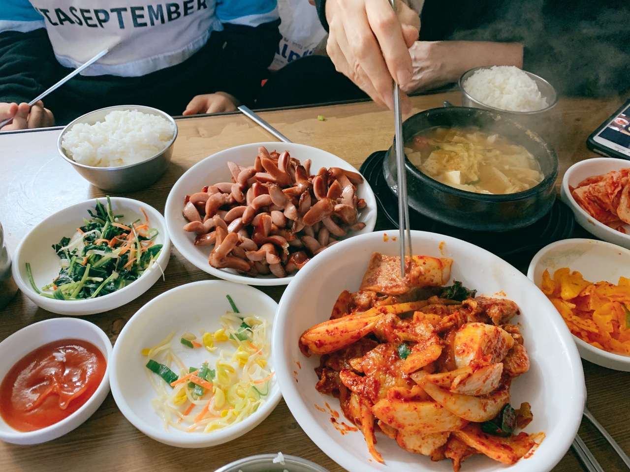 A full table spread of spicy pork, stew, and various side dishes at Ujeong Restaurant.