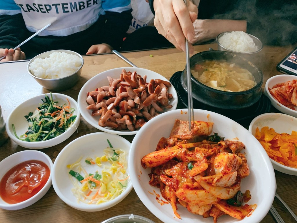 A full table spread of spicy pork, stew, and various side dishes at Ujeong Restaurant.