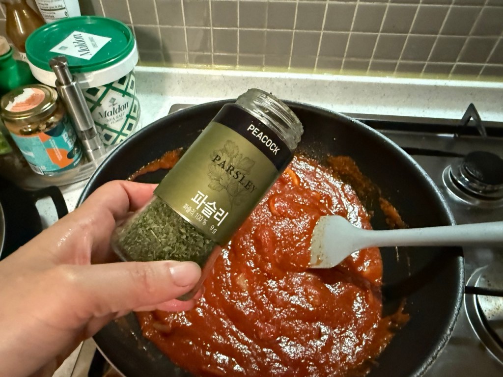 Adding some of paesley to the pan with sautéed ingredients.