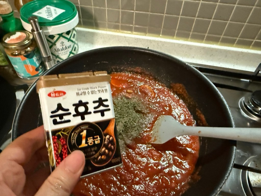 Adding some of pepper to the pan with sautéed ingredients.