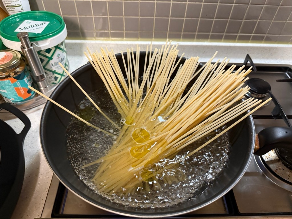 Boiling spaghetti noodles in a pot until they reach the perfect texture.