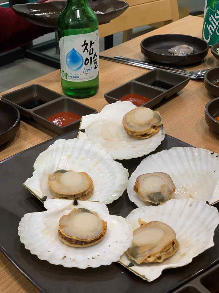 Various types of fresh abalones, clams, and scallops neatly arranged for sale.