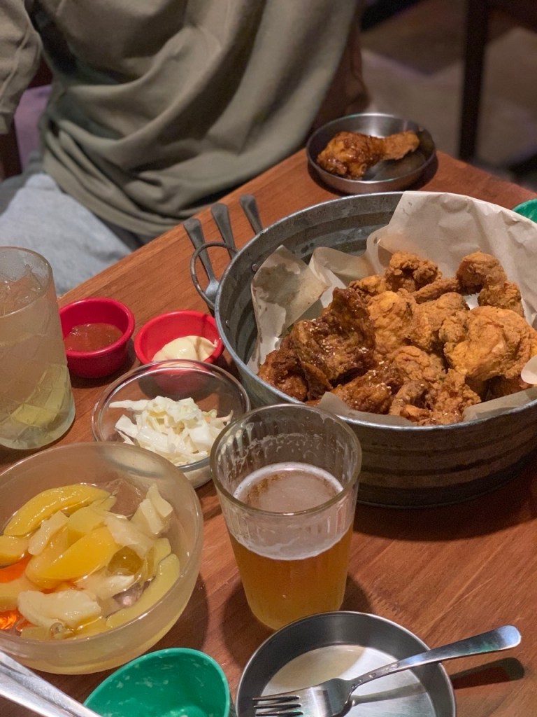 A golden crispy fried chicken platter served with a refreshing glass of beer.