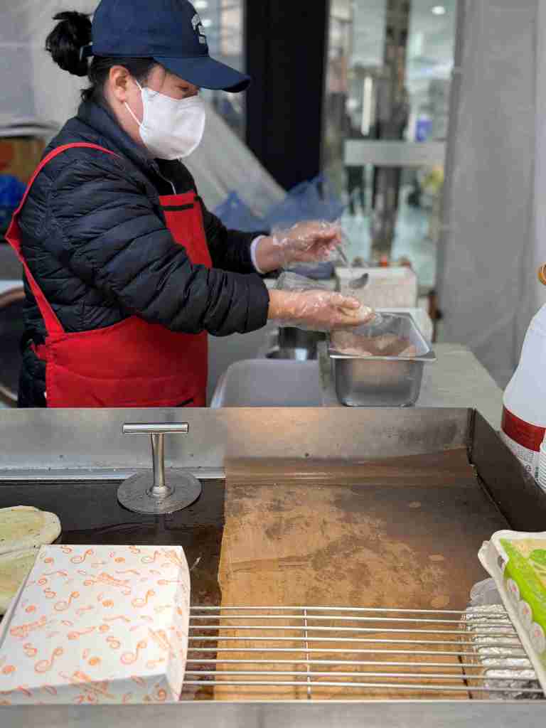 The expert hands of the owner shaping the Hotteok dough with precision.