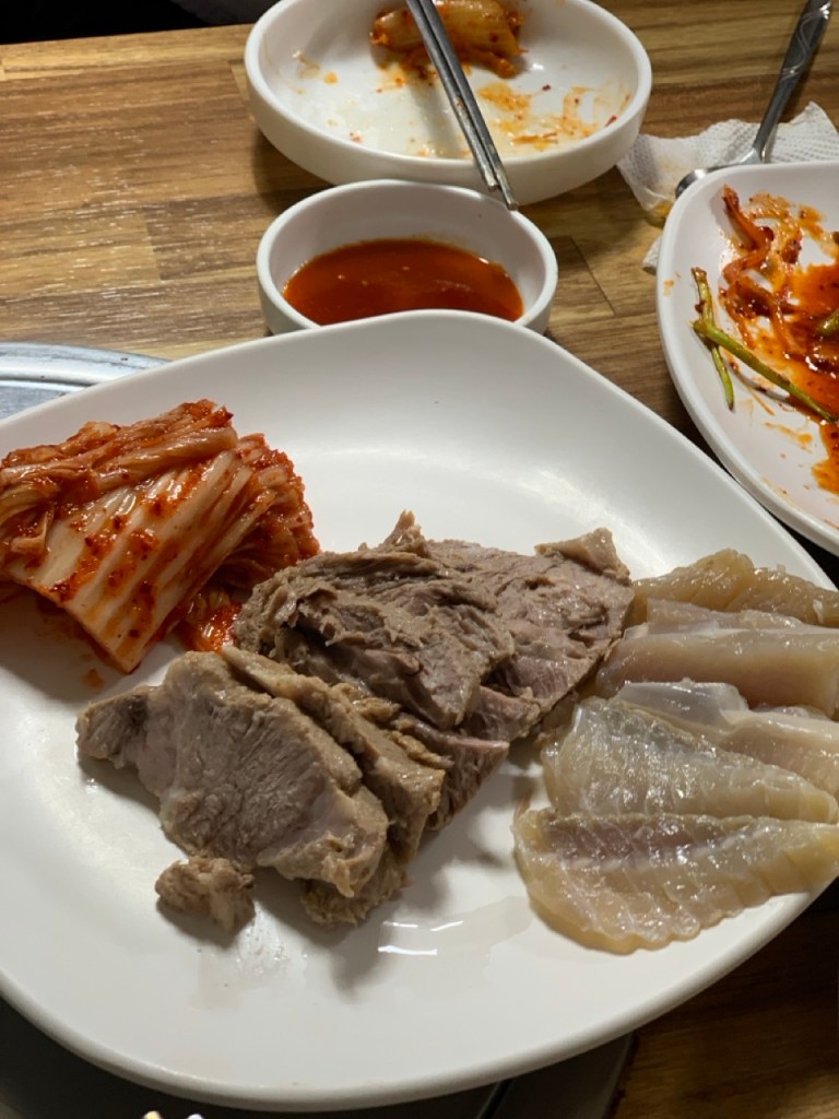 A perfect combination of pork, skate, and kimchi stacked together for a bite.