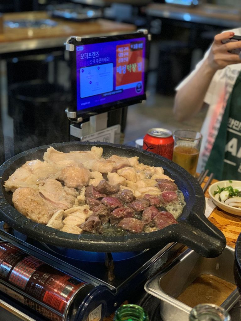 A mouth-watering view of thick beef intestines and abomasum grilling on a hot plate.