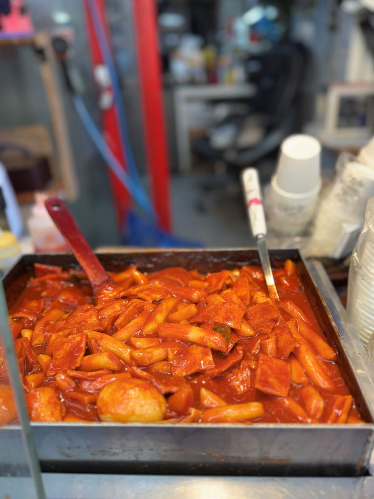 Bright red, chewy tteokbokki served in a bowl, the soul food of Korean street life.