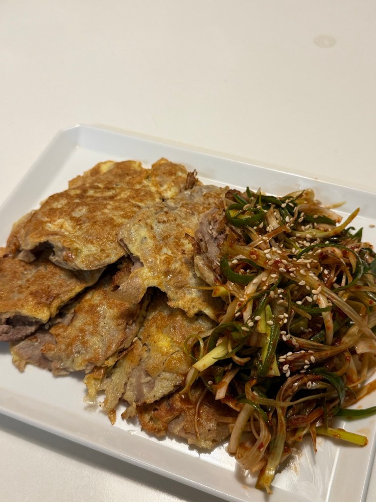 A plate of golden-brown pan-fried beef pancakes garnished with red chili.