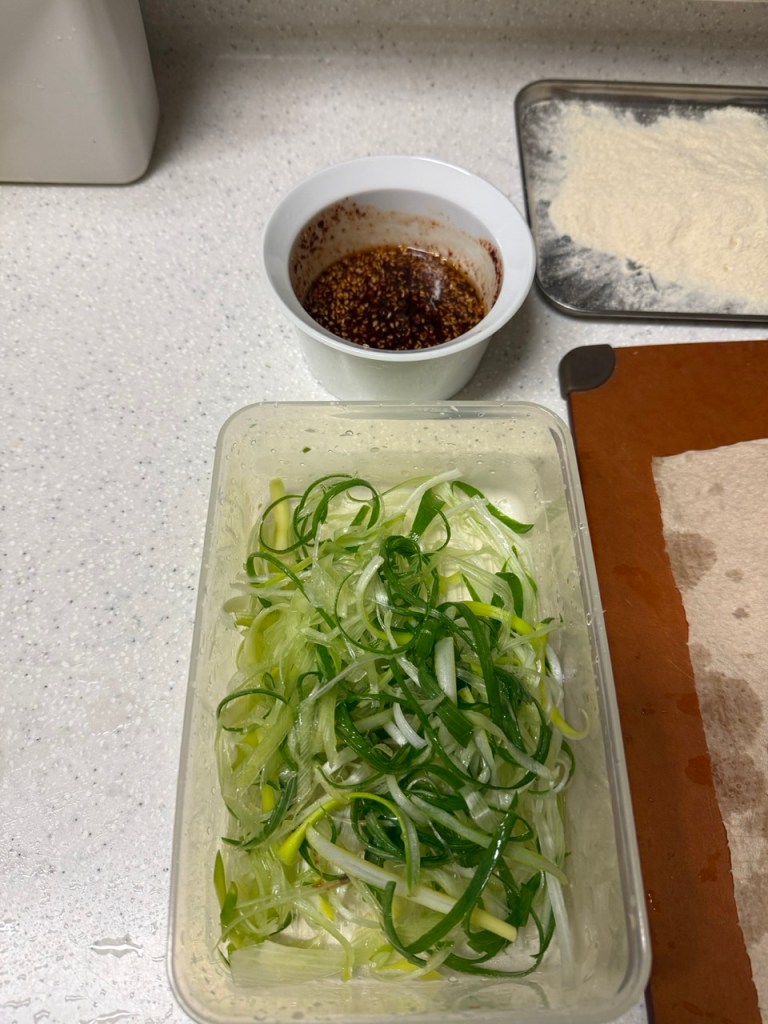 Thinly shredding fresh green onions to create a crisp and spicy salad base.