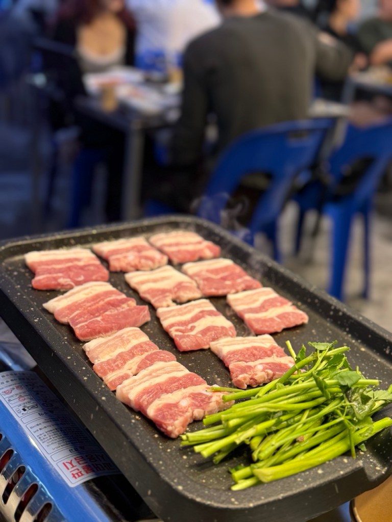 Close-up shot of pork belly and kimchi grilling to perfection on a hot plate.