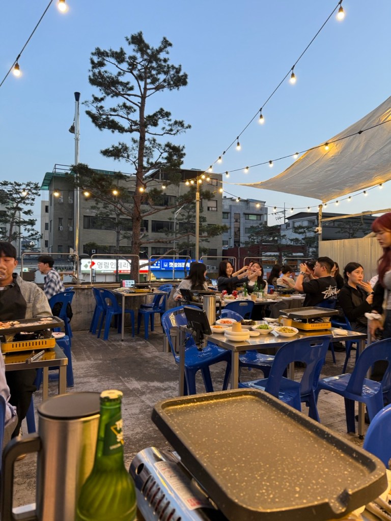 A lively street view filled with outdoor tables and people enjoying BBQ.