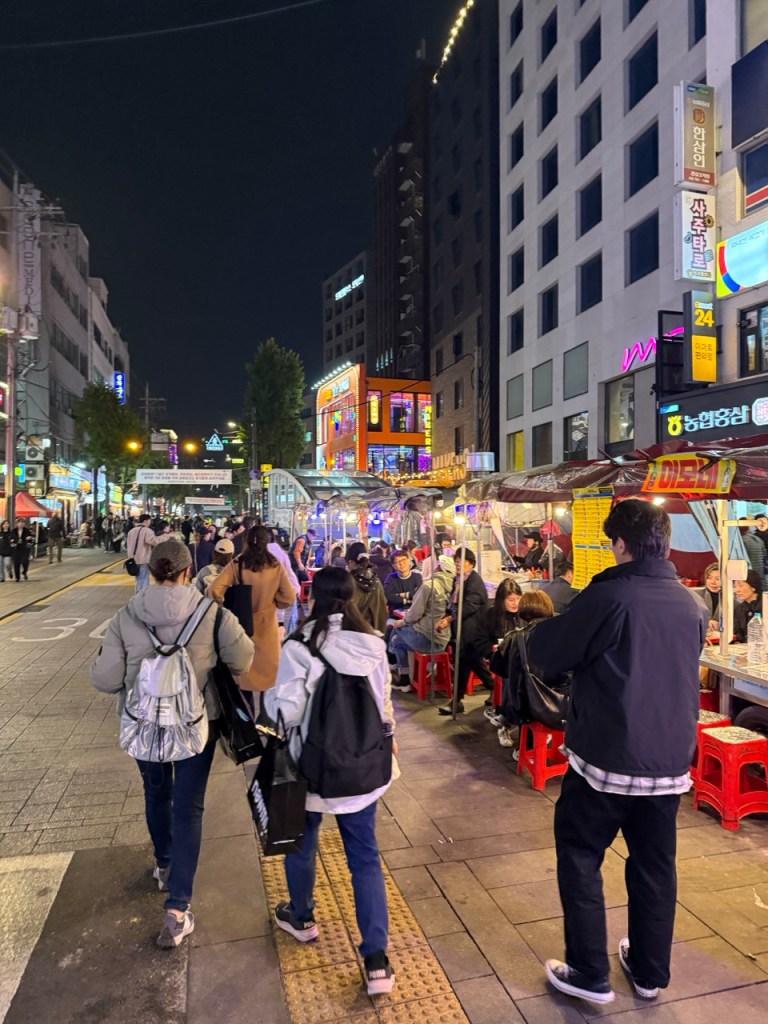 A row of glowing orange tents illuminating the historic Nakwon-dong alley at night.