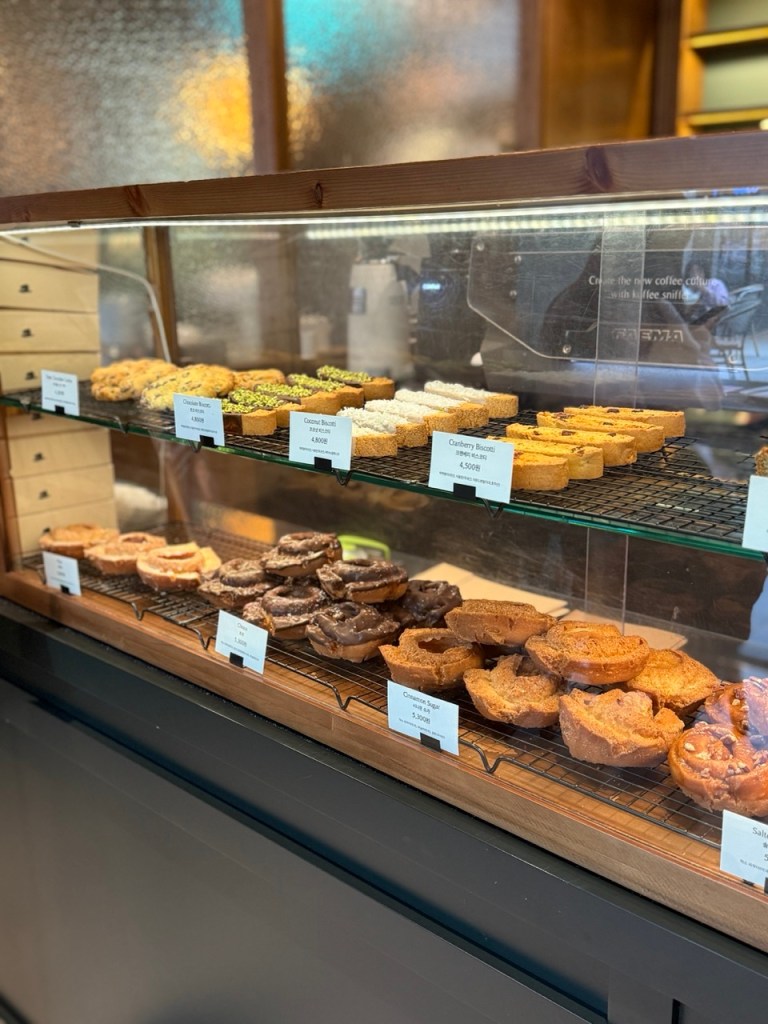 A moody shot of various donuts arranged on the classic wooden counter.