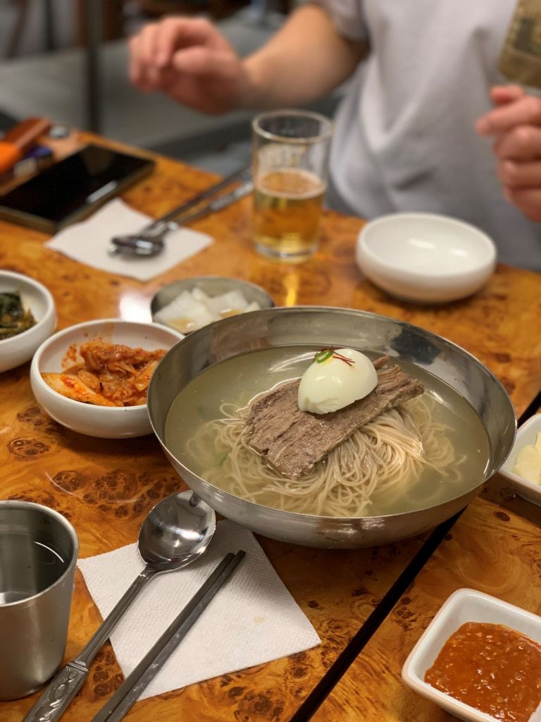 A bowl of authentic Pyongyang naengmyeon with clear broth and buckwheat noodles.