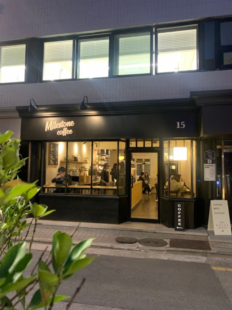 The cozy and sophisticated night view of the cafe with warm amber lights.