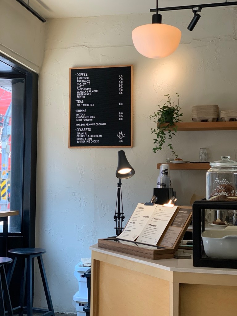 The aesthetic contrast between the dark black wall and warm wooden furniture outside.