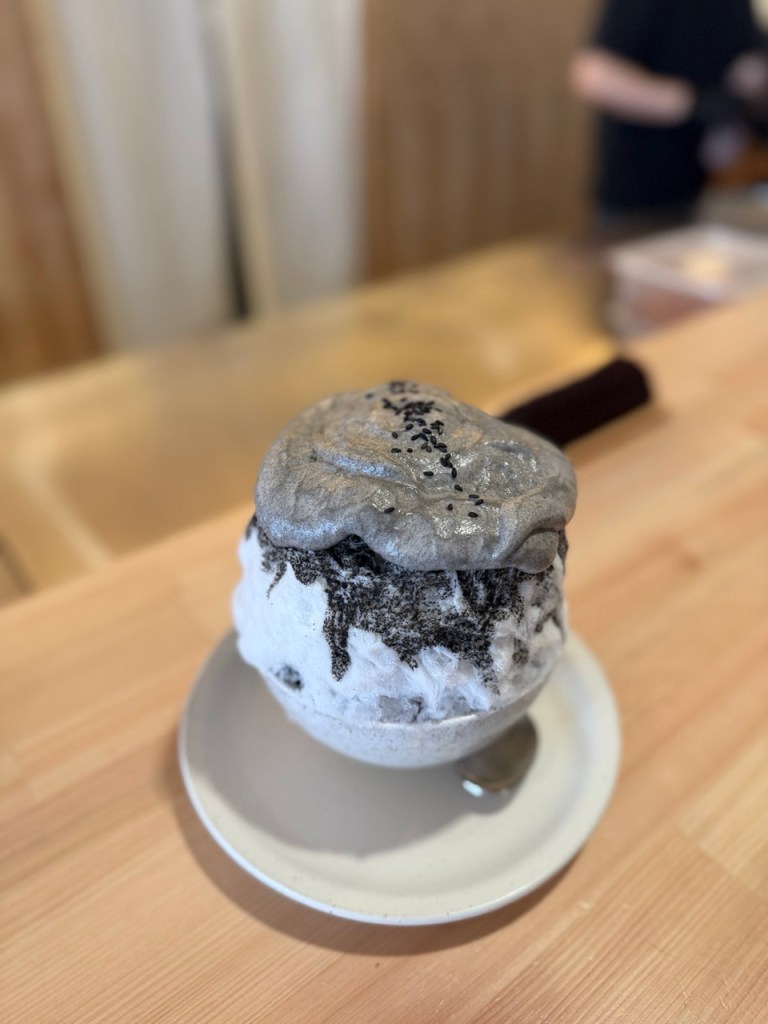 White milk ice peeking through a rich layer of black sesame powder.