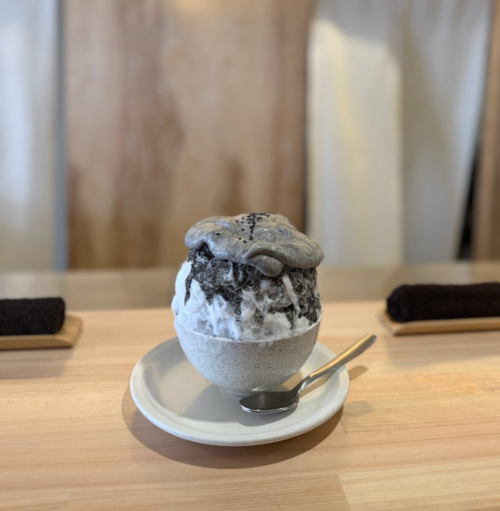 A neatly arranged tray of black sesame bingsu with traditional toppings at Koriya.