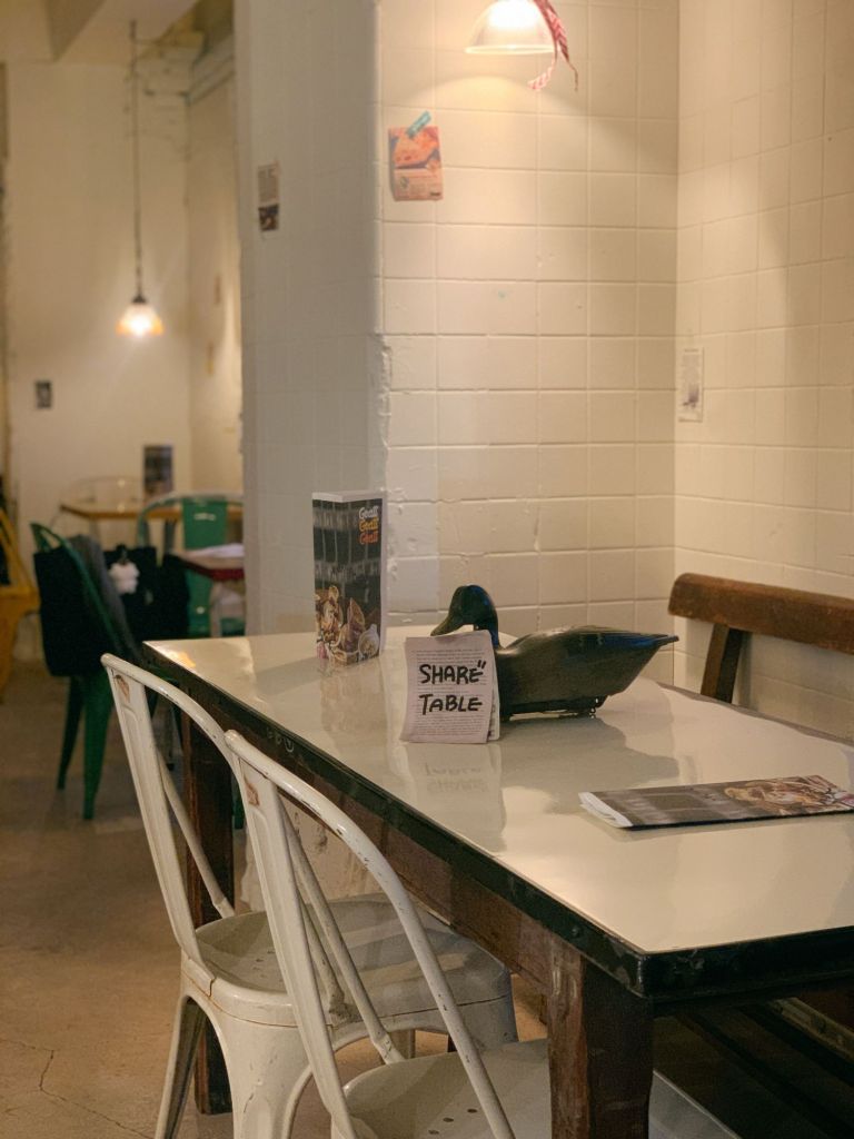 The warm and nostalgic interior of GOAT DELI, featuring wooden furniture and soft lighting.