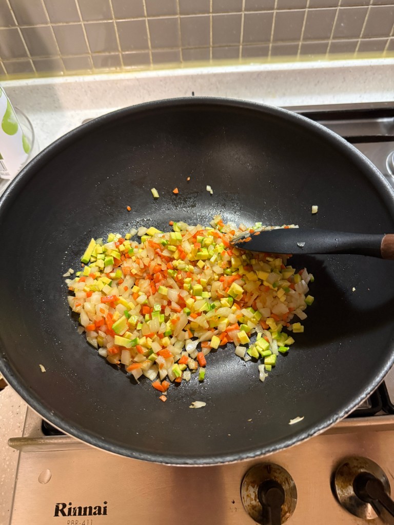 Sautéing colorful minced vegetables in sesame oil to enhance the flavor.