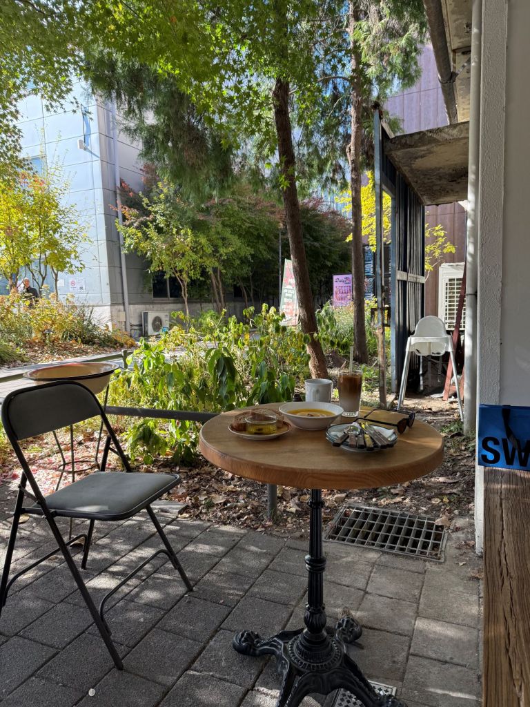 The charming, European-style outdoor terrace seating of Friends and Yard cafe, surrounded by lush green plants near Seoul Forest.