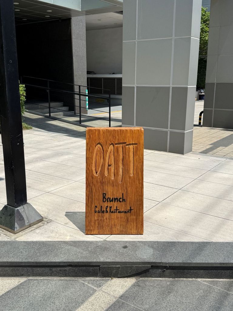 The stylish main entrance and minimalist wooden signboard of brunch cafe OATT in Seongsu-dong.