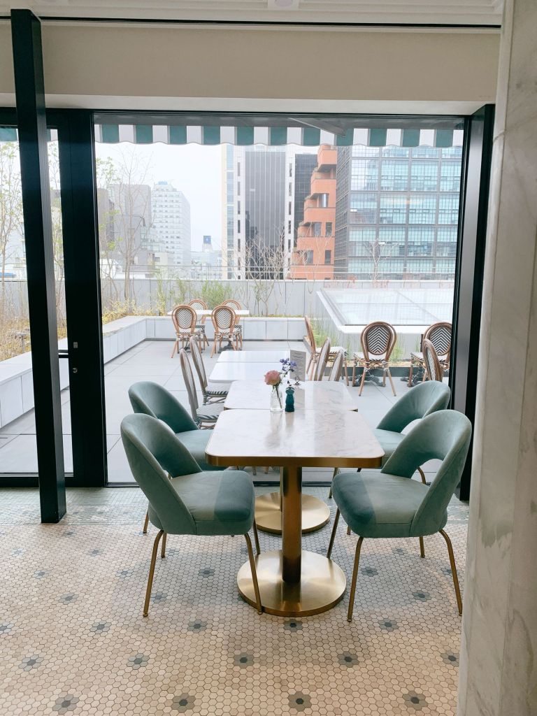 The sophisticated, airy, and upscale dining room of Sadelle's Seoul, beautifully decorated with vintage glass and signature blue accents.