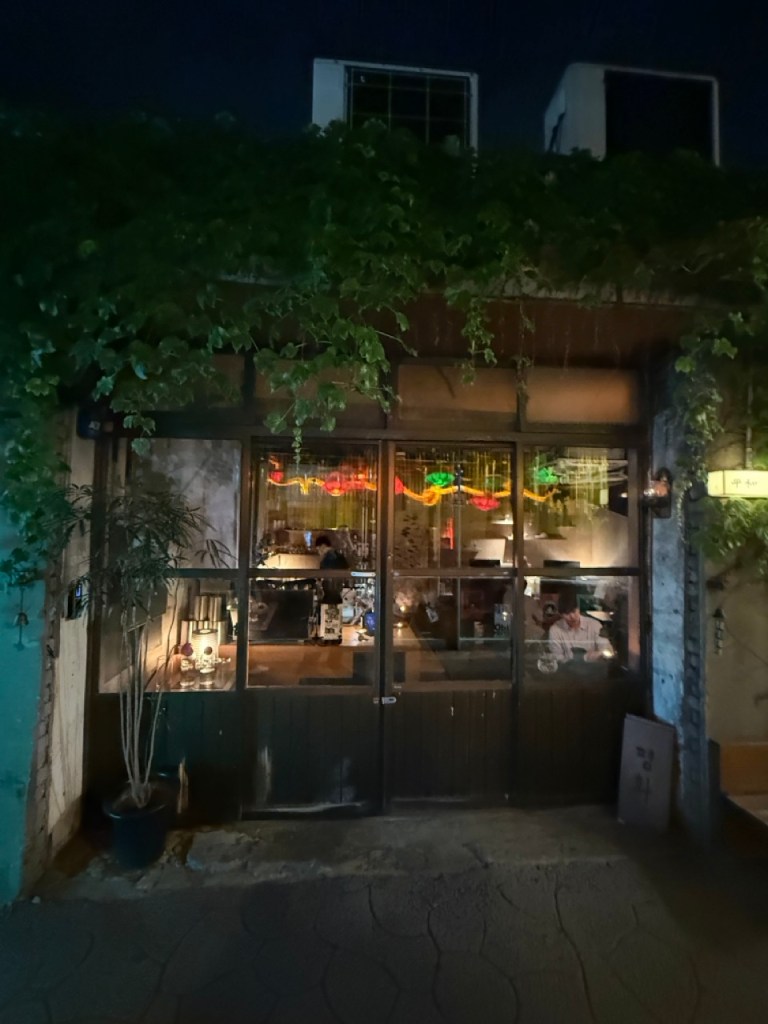 A small, aesthetic wooden sign of Cafe Pyeonghwa in the quiet alleys of Mullae Art Village.