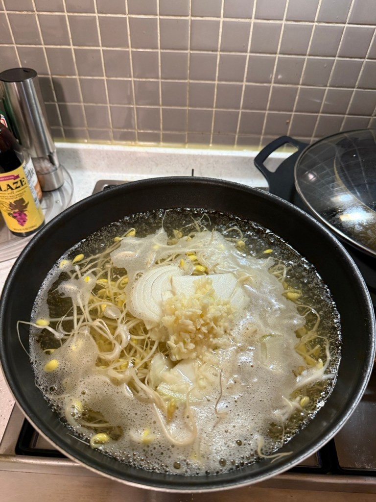 Tossing a generous handful of fresh minced garlic and finely chopped green scallions into the simmering soup pot.