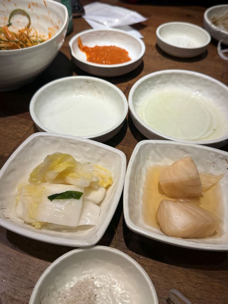 A rich and colorful Samgyeopsal table layout highlighting various onion variations and specialized dipping sauces for the ultimate umami flavor.