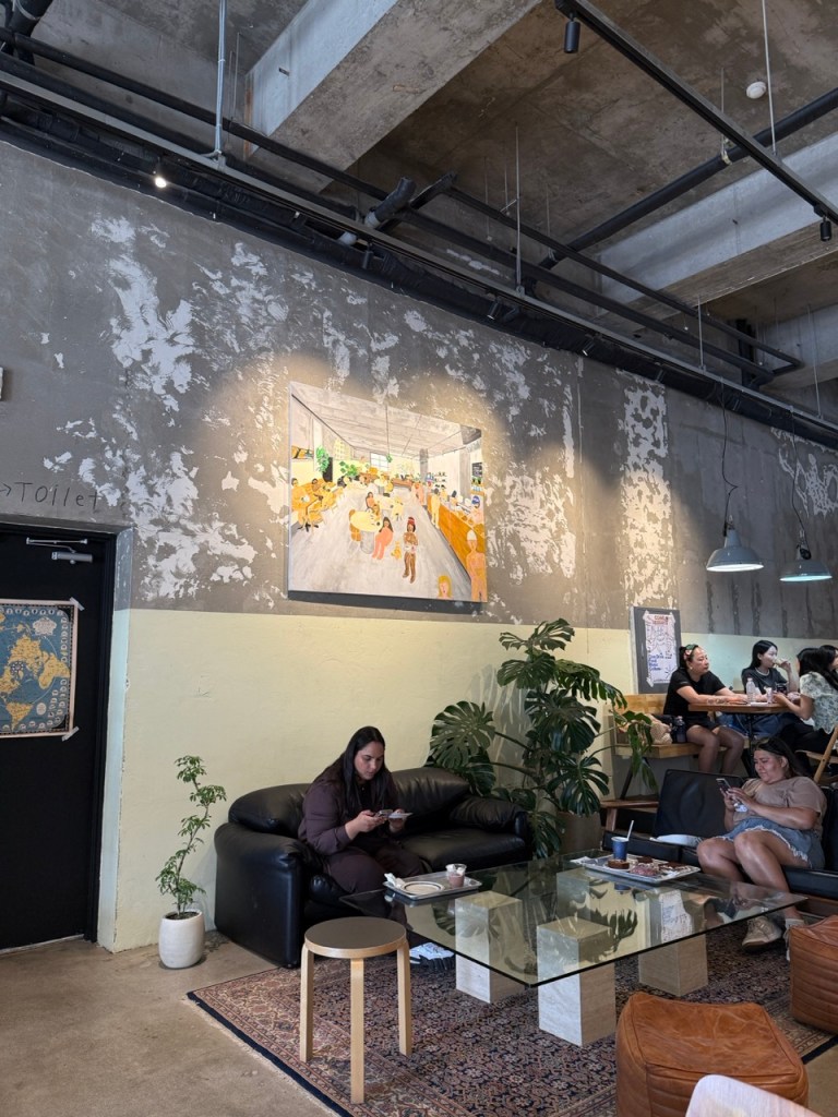 A large group of global K-pop fans capturing memories together next to the artistic objects at BTS RM sister's cafe.