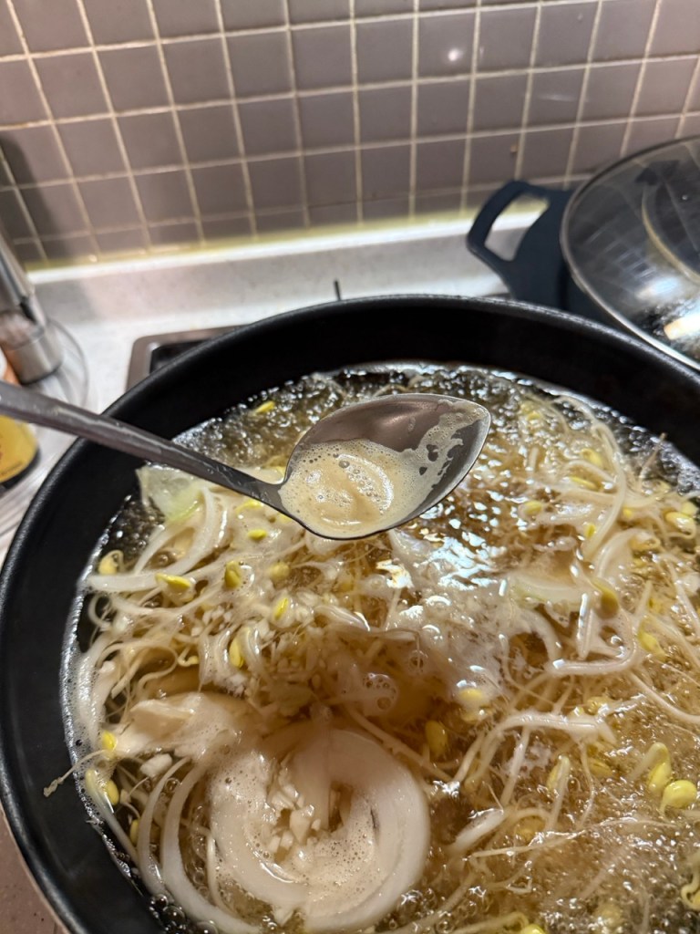 Natural white foam and impurities rising to the surface of the simmering soybean sprout soup as it cooks