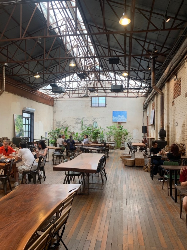A vast and rustic long wooden communal table filled with gourmet coffee and pastries, accommodating a large tour group at Daelim Changgo.
