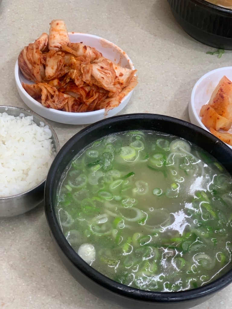 A premium bowl of traditional Korean ox bone soup (Seolleongtang), showcasing a rich, milky-white broth simmered for hours.