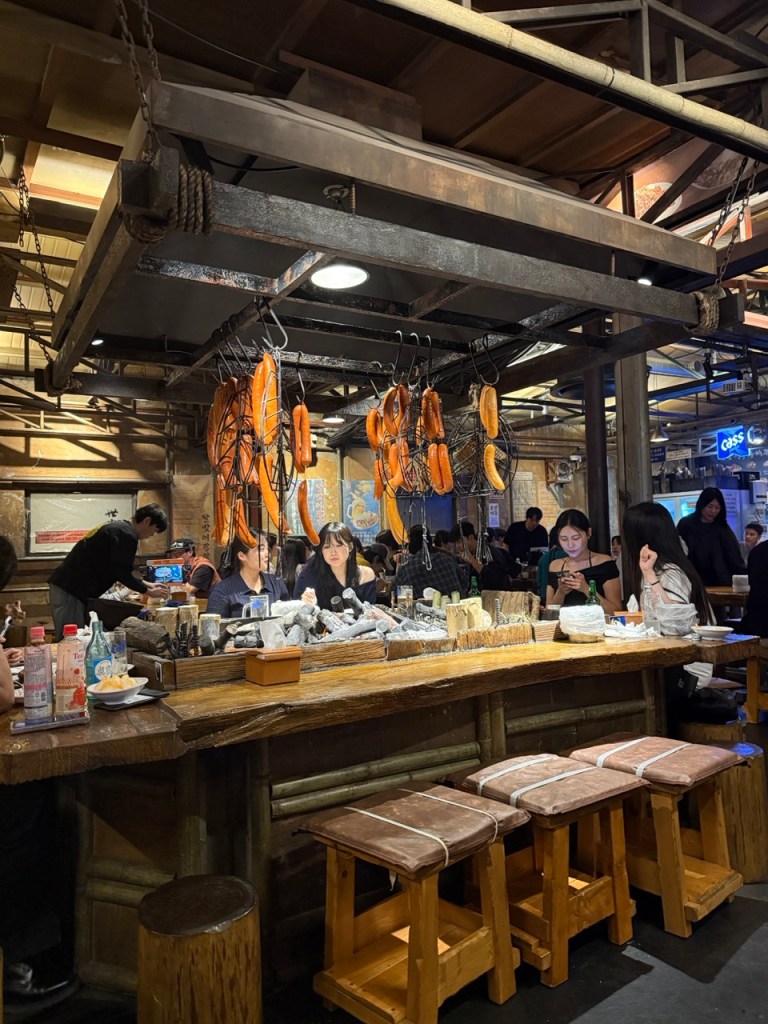 The atmospheric, moody, and lively interior seating layout of Dalmai Square BBQ, packed with trendy local youth.