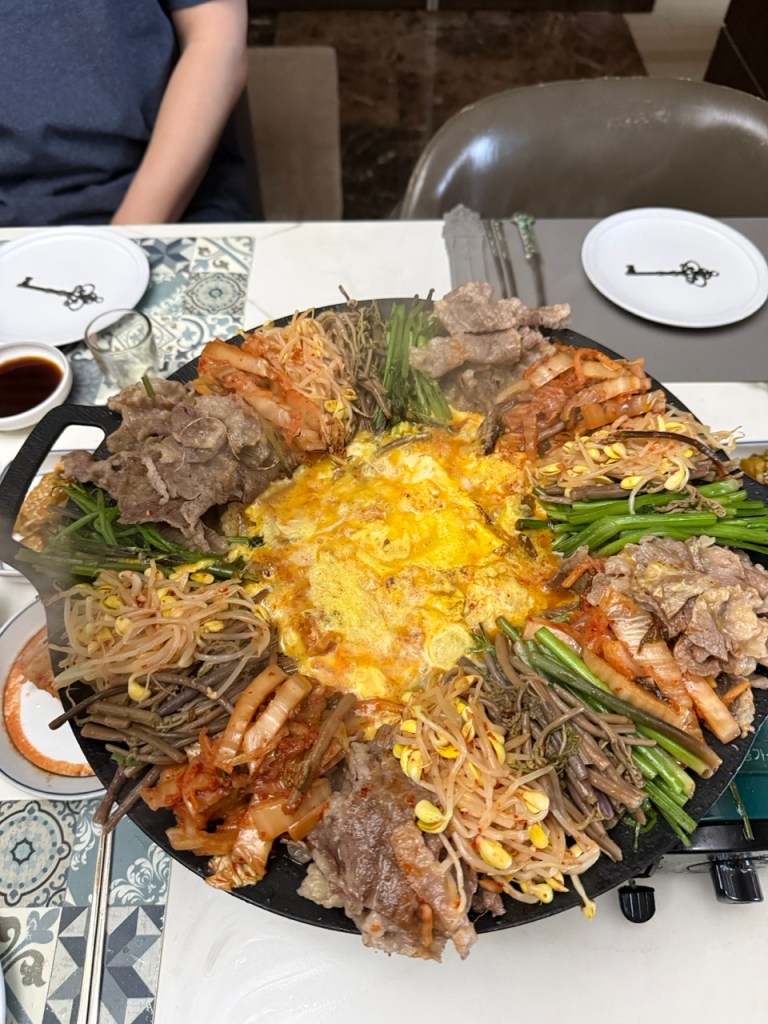 A high-satisfaction top-down view of a modern Korean beef brisket Korean BBQ platter featuring colorful vegetables and a steamed egg center.