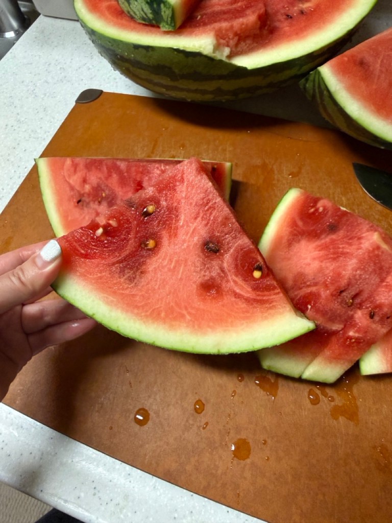 A cinematic focus on a neat row of vibrant triangular watermelon slices glistening under natural summer light.